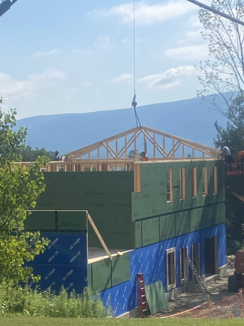 Construction of a wooden-framed house with a mountainous backdrop.