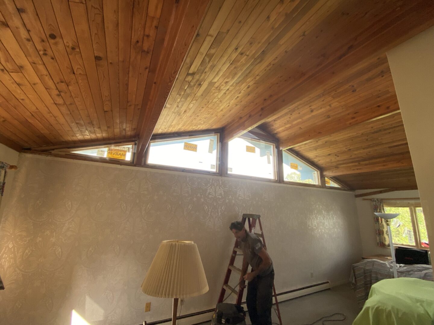 Wood-paneled ceiling with triangular windows above a beige wall.