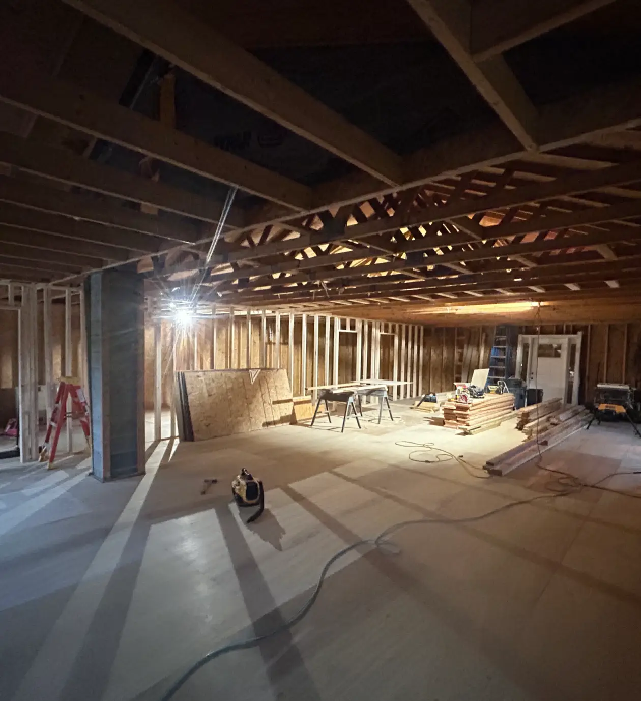 Unfinished basement with exposed beams and tools.