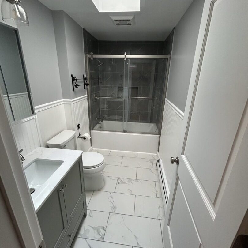 Modern bathroom with a glass shower enclosure and marble floor tiles.