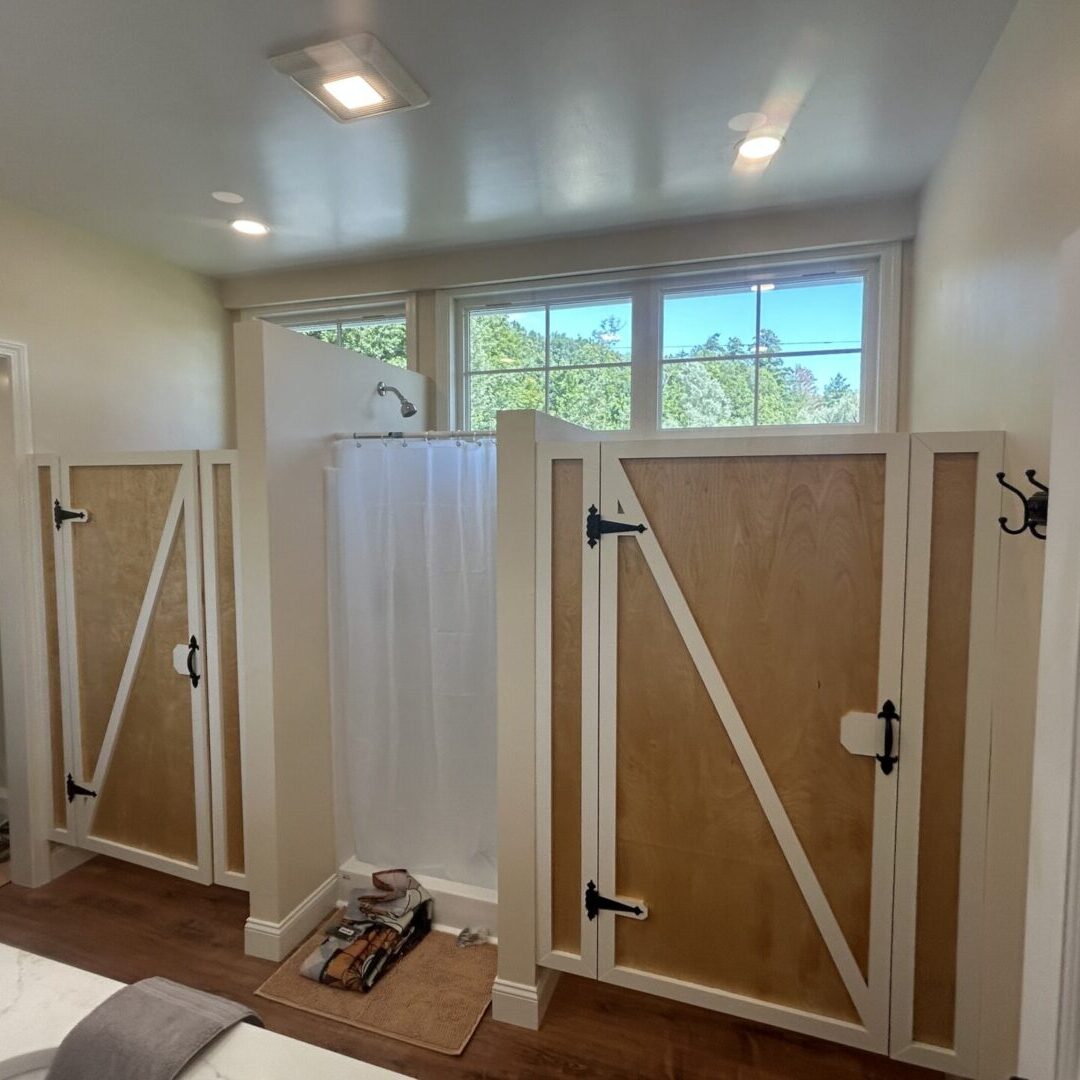 Rustic wooden stalls with white curtains in a stable.