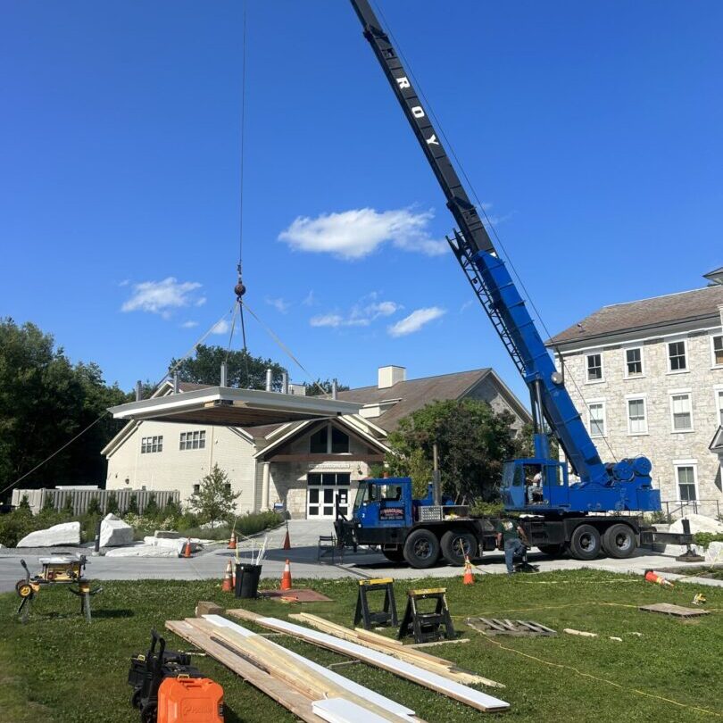 A blue crane lifting materials near buildings under a clear sky.